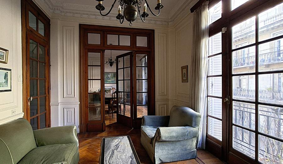 Living y, al fondo, el comedor, vistos a través de puertas vidriadas de madera